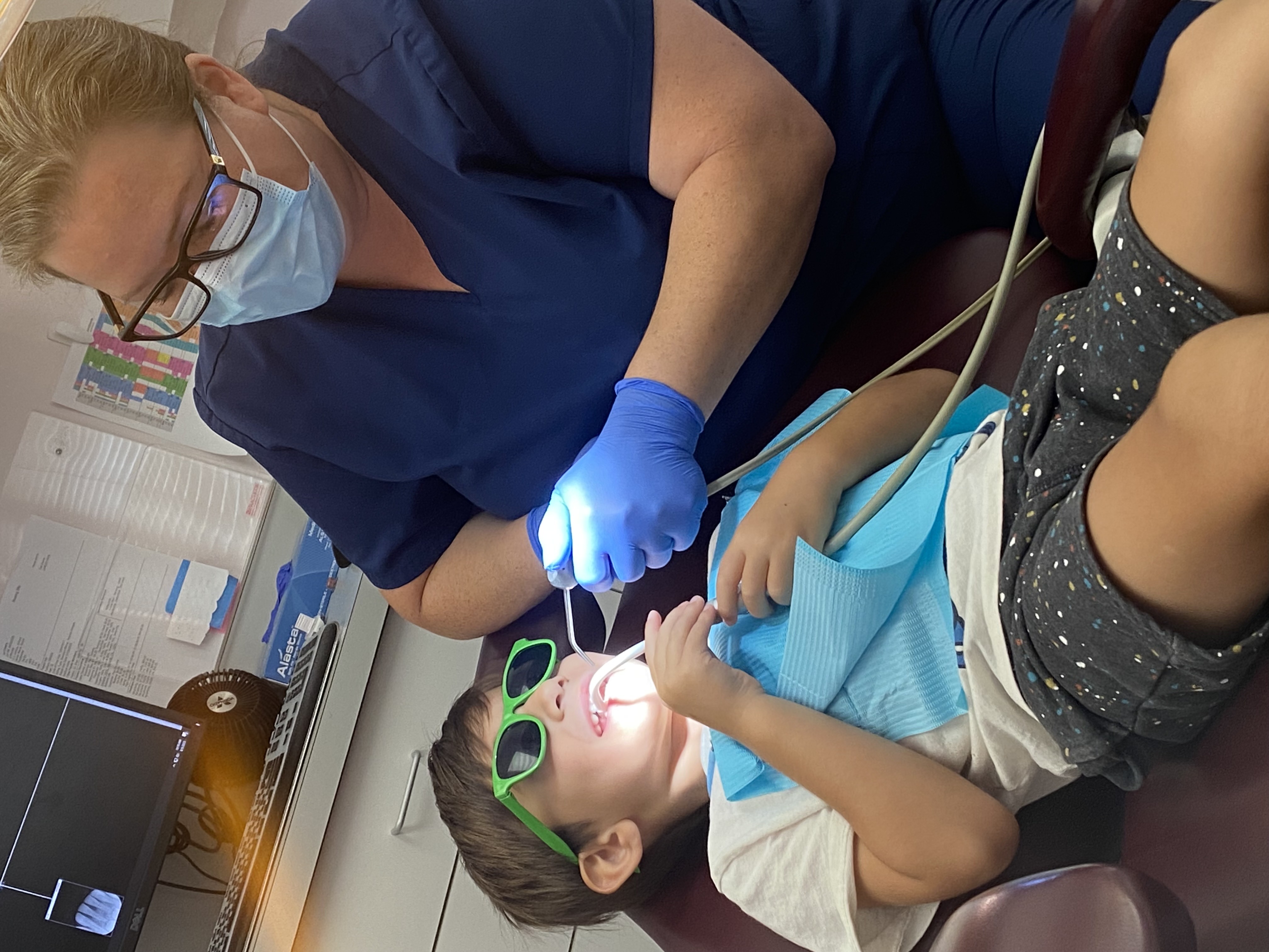 Hygienist with young patient wearing fun sunglasses
